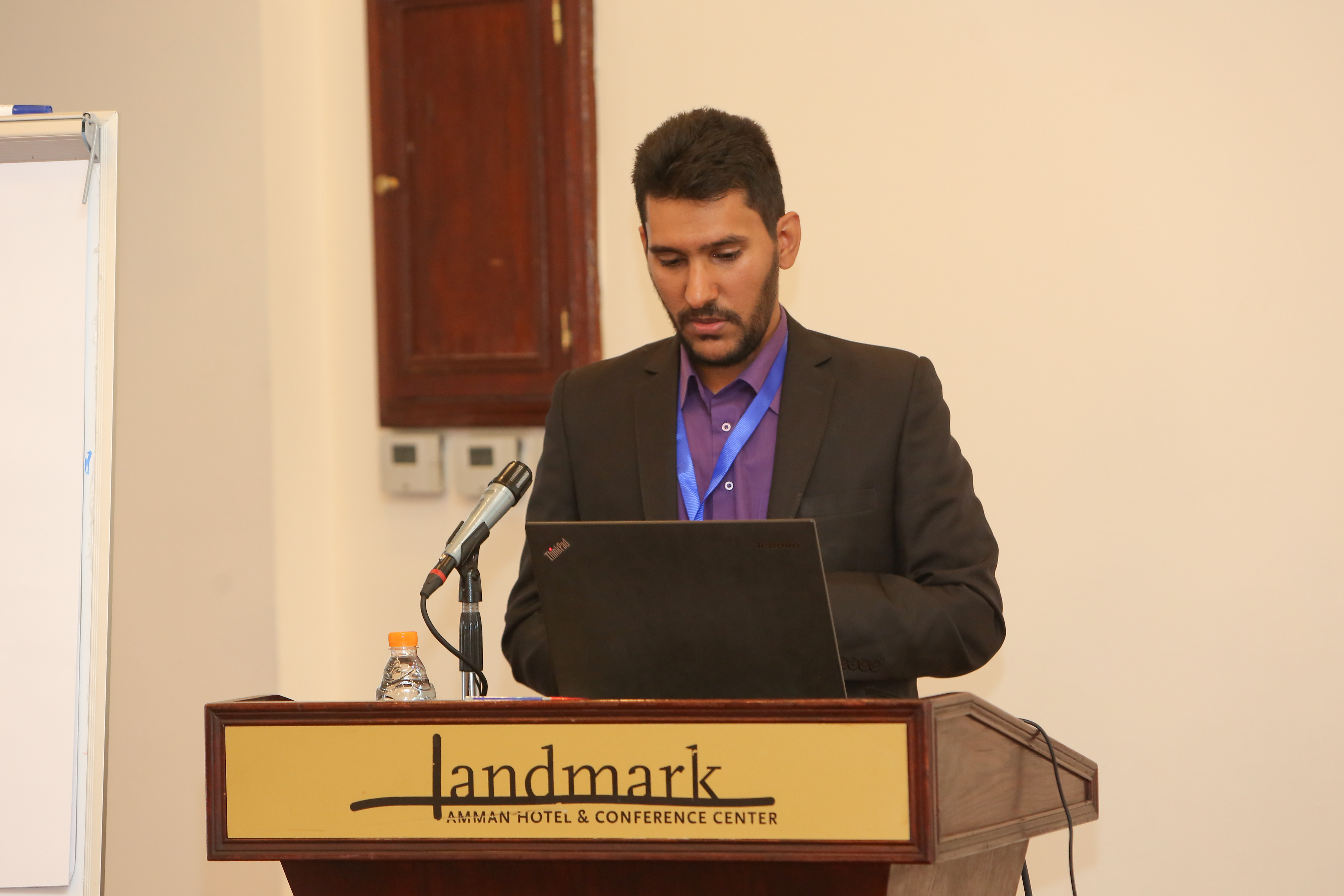 Muayyad Alsadi speaking from a laptop at a podium in Amman.